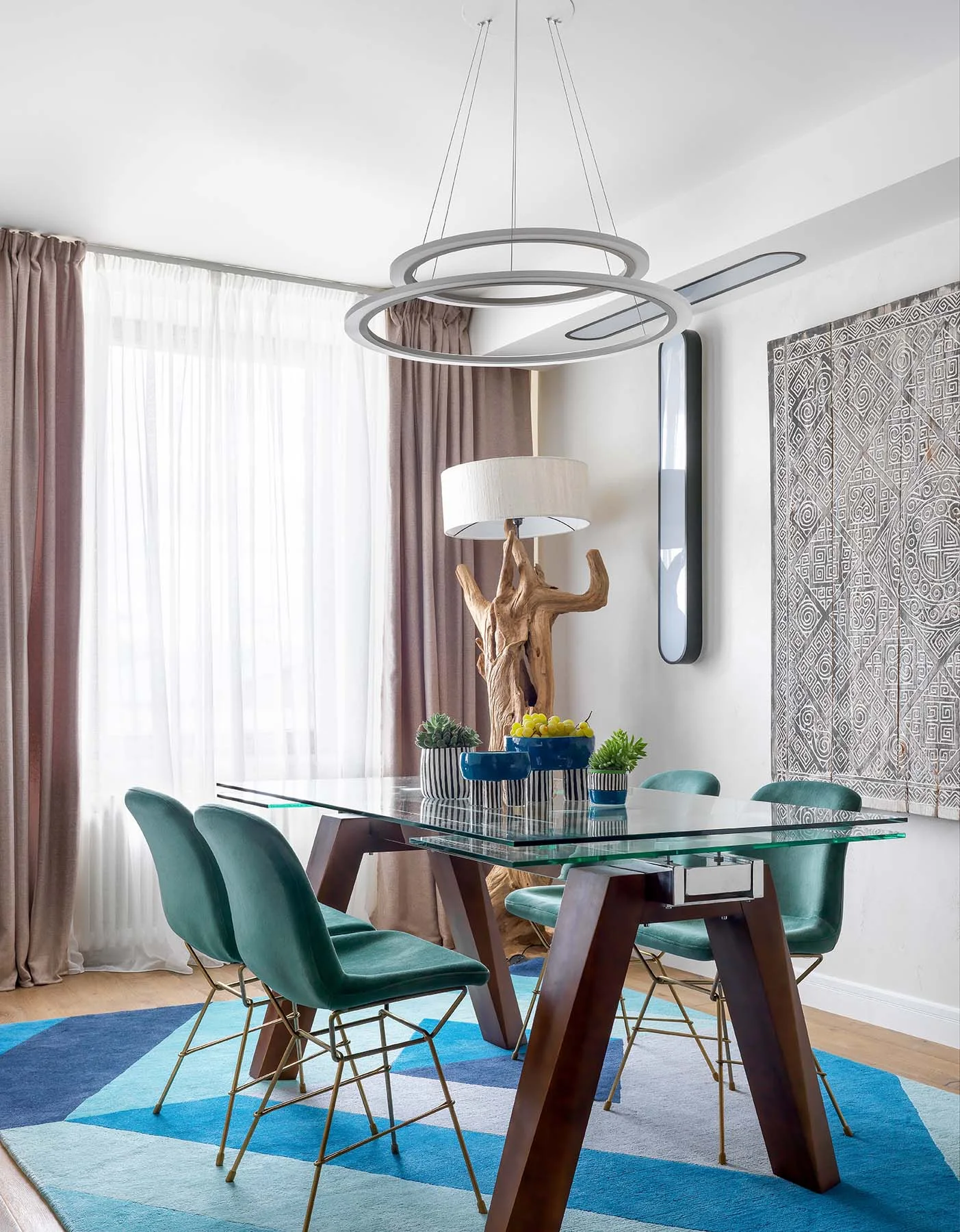 Comedor de un apartamento en Moscú con sillas turquesa, alfombra azul, lámpara escultórica y arte textil.