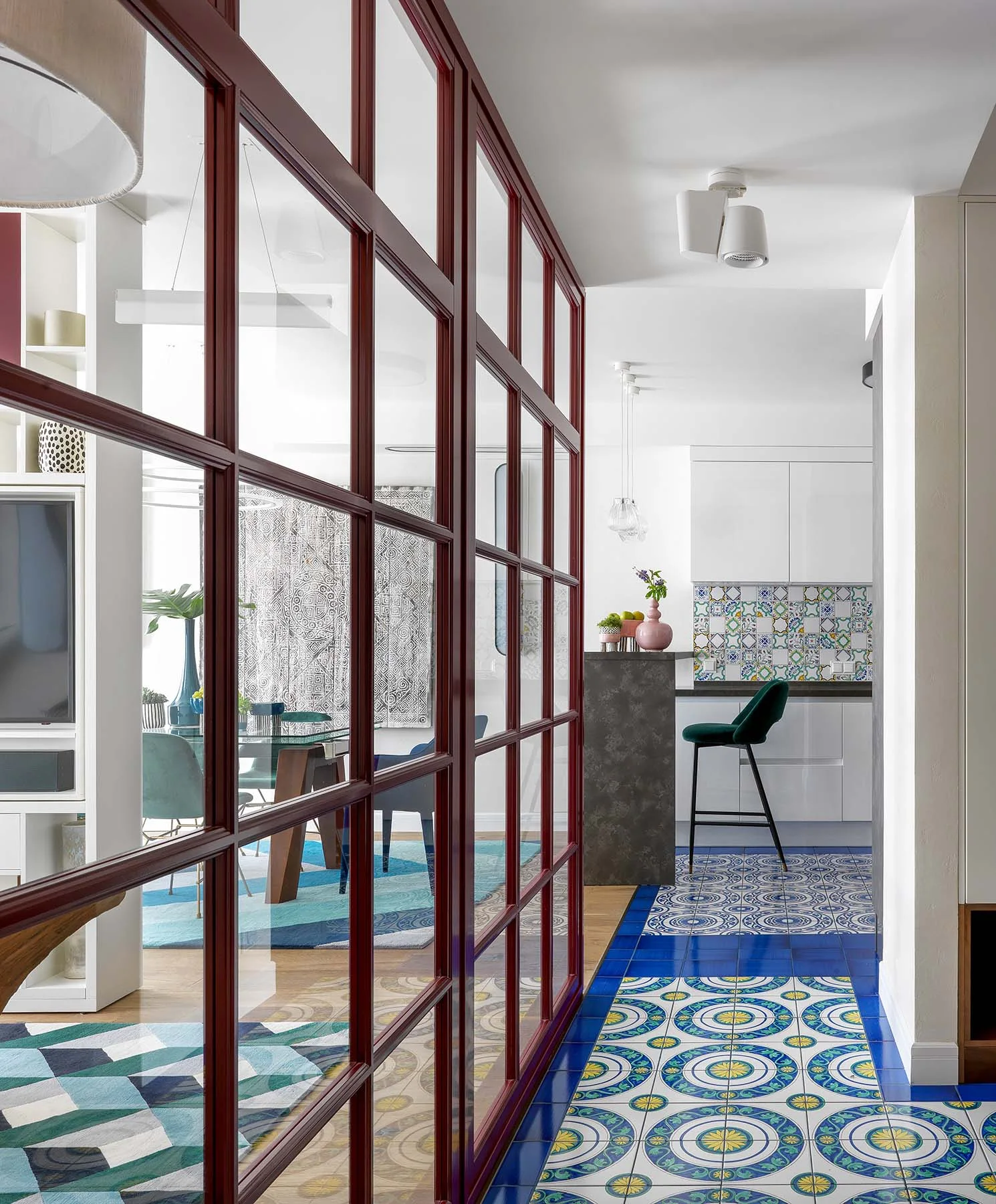 Pasillo de un apartamento en Moscú con cerramiento burdeos, cocina blanca y baldosas multicolores.