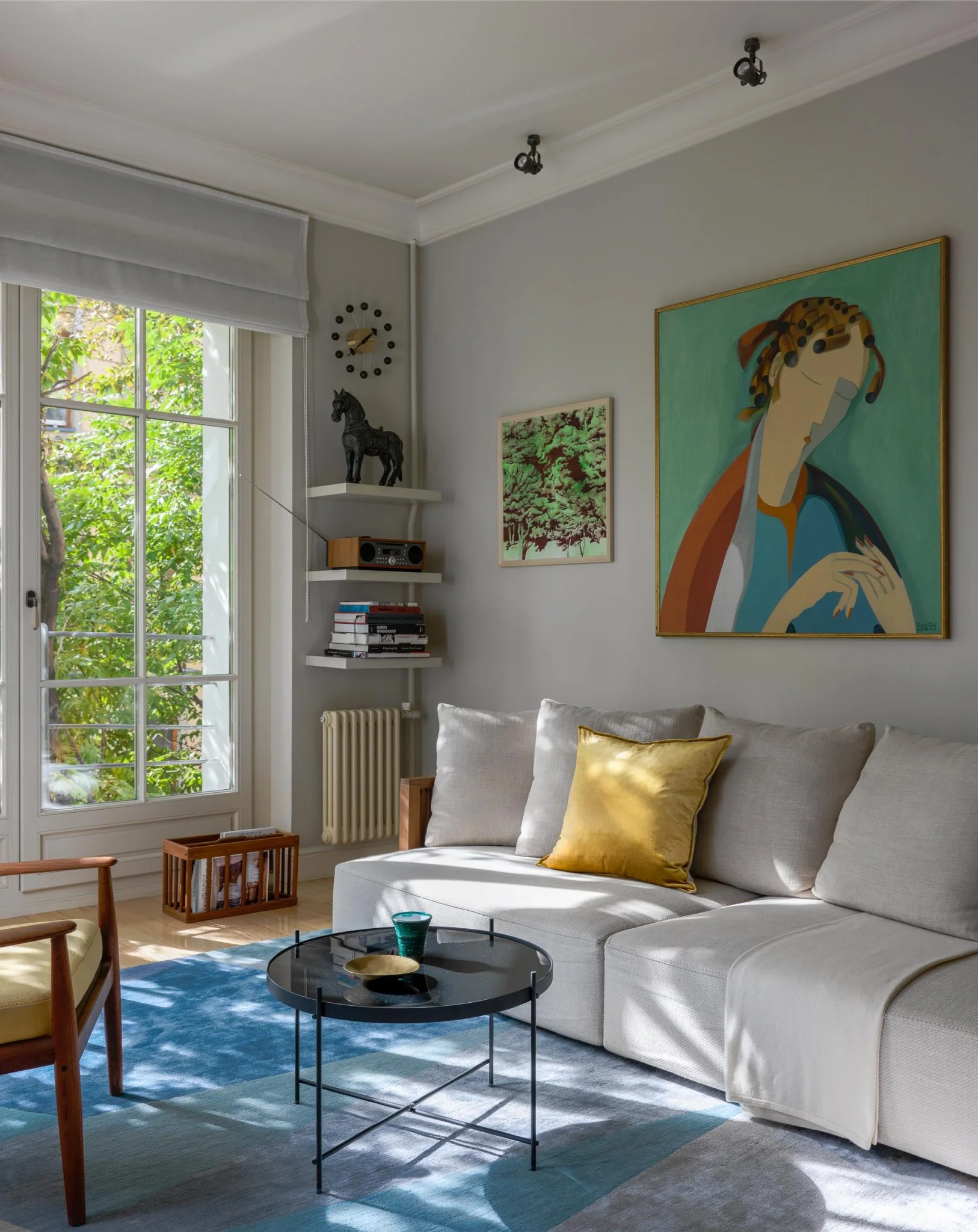 Detalle de un salón en Moscú con sofá gris y retrato contemporáneo de colores intensos.