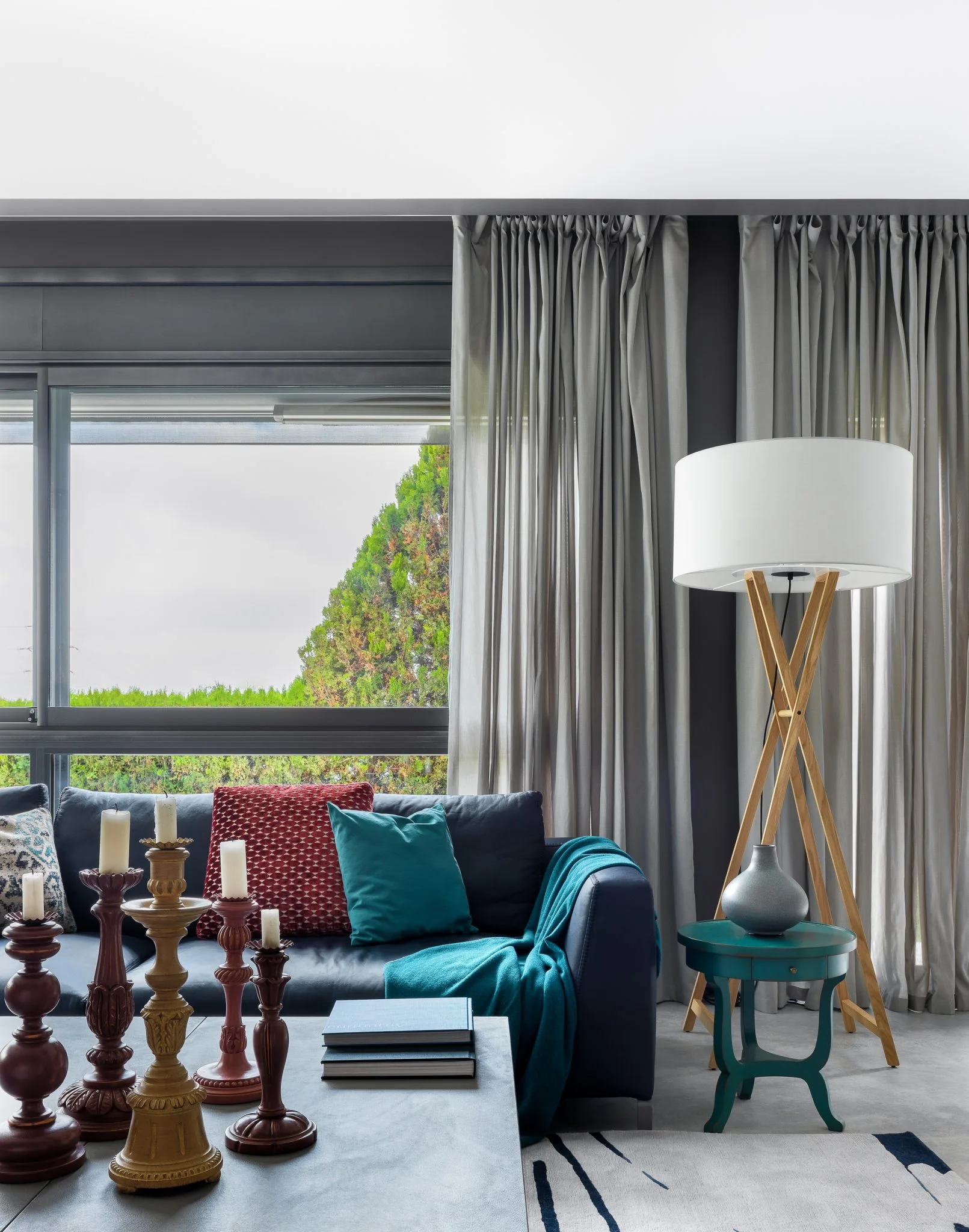 Zona de estar de una vivienda en Barcelona con sofá azul, textiles turquesa y ventanales al jardín.