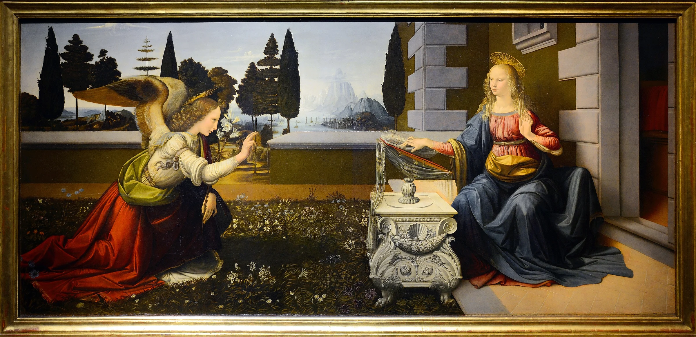 La Anunciación de Leonardo da Vinci, el arcángel Gabriel arrodillado ante María en un jardín renacentista.